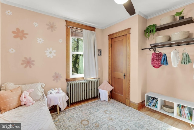 bedroom featuring baseboards, radiator, wood finished floors, and crown molding