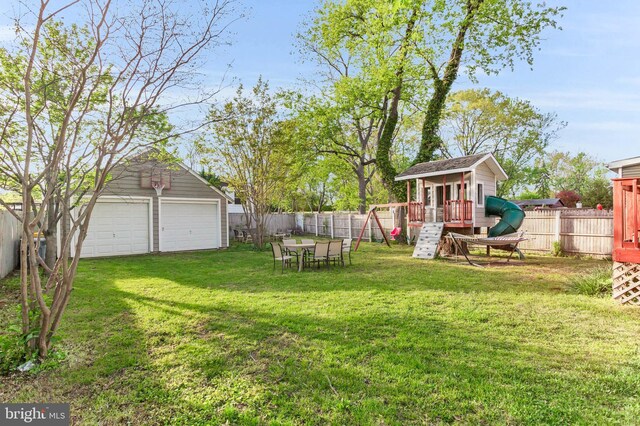 view of yard featuring an outdoor structure, a fenced backyard, a detached garage, and a playground