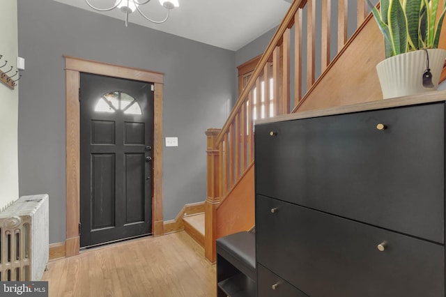 entryway with stairway, baseboards, light wood finished floors, and radiator