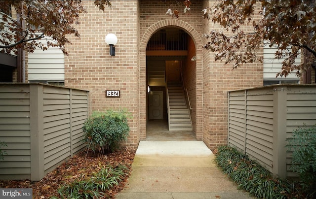 entrance to property featuring fence and brick siding