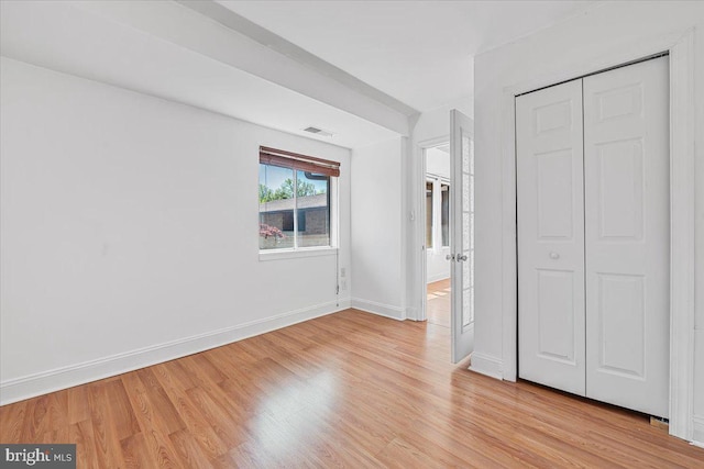 unfurnished bedroom featuring visible vents, baseboards, a closet, and light wood-type flooring
