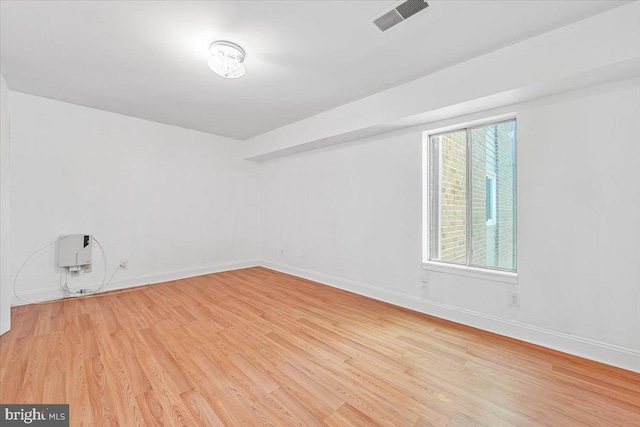 spare room featuring baseboards, light wood-type flooring, and visible vents