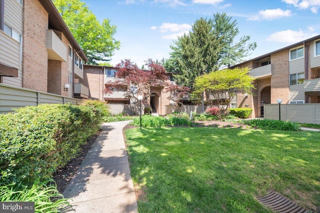 view of home's community with a lawn and fence