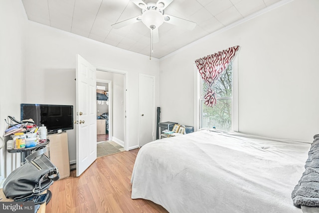 bedroom with ornamental molding, light wood-style flooring, and a ceiling fan