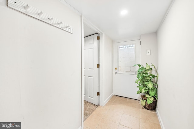 doorway featuring light tile patterned floors and baseboards