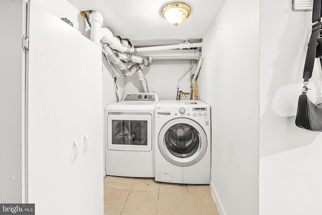 washroom featuring washing machine and clothes dryer, light tile patterned flooring, and laundry area