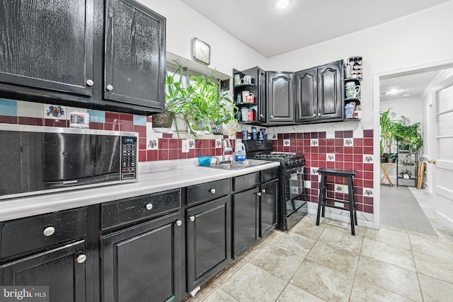 kitchen with open shelves, stainless steel microwave, a sink, dark cabinetry, and black gas range