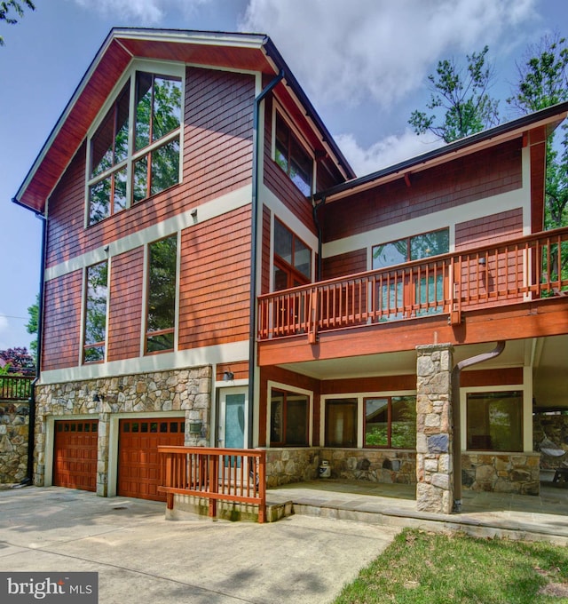 6525 76th St, Cabin John, MD 20818 - view of front of home featuring stone siding, a garage, concrete driveway, and a balcony
