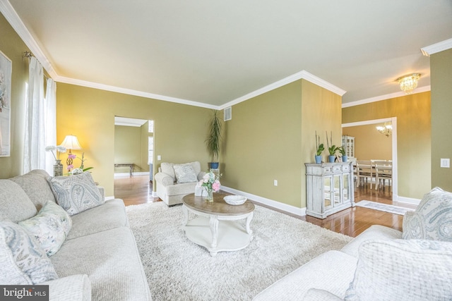 living room featuring wood finished floors, ornamental molding, baseboards, and a notable chandelier