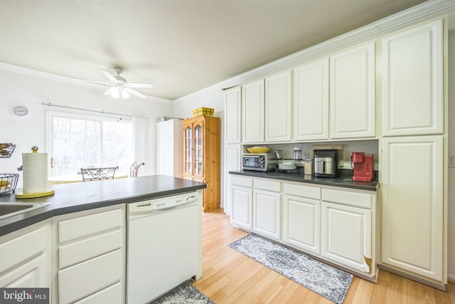 kitchen with white dishwasher, dark countertops, light wood-style flooring, and white cabinets