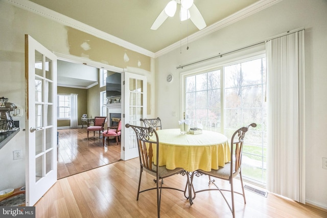dining space featuring french doors, light wood-style flooring, visible vents, ceiling fan, and ornamental molding