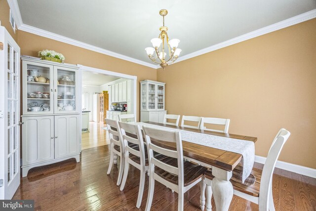 dining room with baseboards, wood finished floors, a notable chandelier, and ornamental molding
