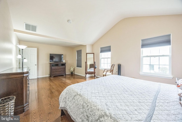 bedroom featuring vaulted ceiling, wood finished floors, visible vents, and baseboards