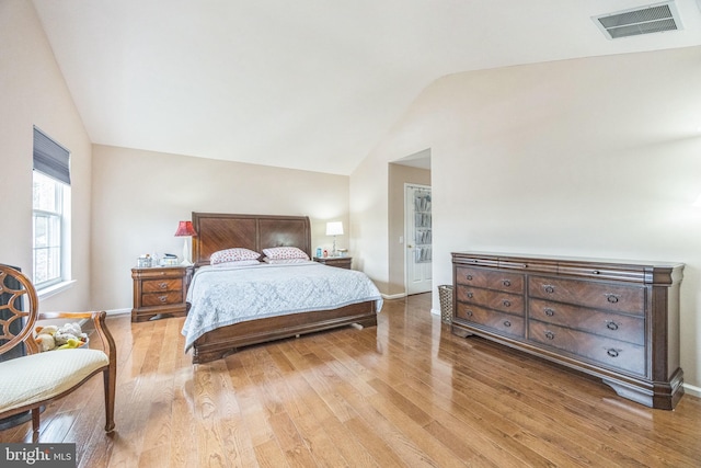 bedroom featuring lofted ceiling, light wood-style floors, visible vents, and baseboards