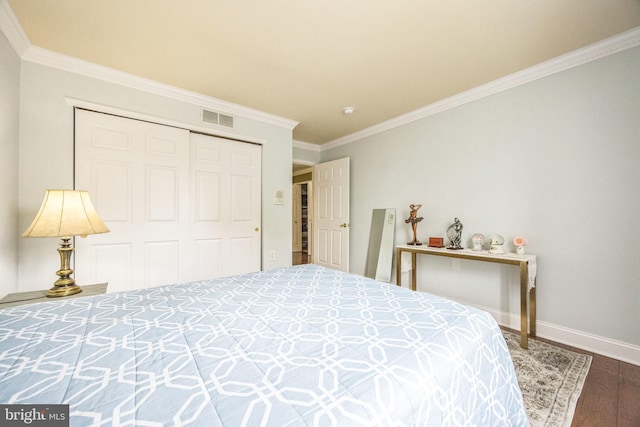 bedroom with wood finished floors, a closet, baseboards, ornamental molding, and visible vents