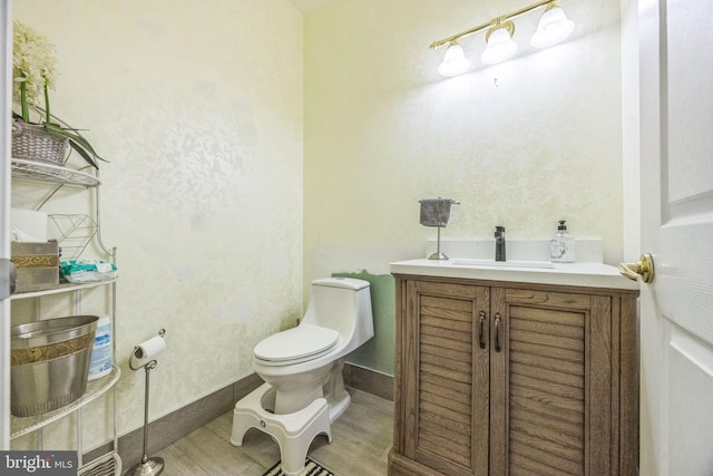 half bath with wood finished floors, vanity, and toilet