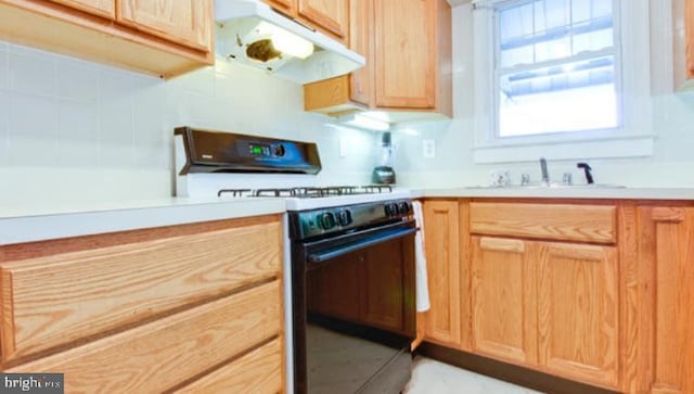 5010 54th Pl, Hyattsville, MD 20781 - kitchen featuring decorative backsplash, under cabinet range hood, light countertops, a sink, and range with gas stovetop