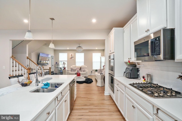 kitchen with a sink, open floor plan, light countertops, and appliances with stainless steel finishes