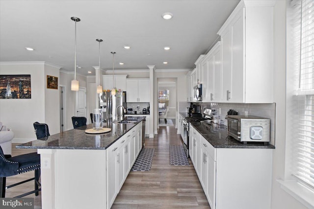 kitchen featuring a kitchen breakfast bar, ornamental molding, recessed lighting, stainless steel appliances, and a sink