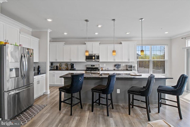 kitchen with tasteful backsplash, dark countertops, crown molding, white cabinetry, and stainless steel appliances