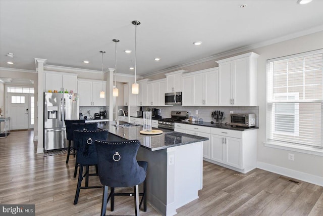 kitchen featuring tasteful backsplash, a sink, appliances with stainless steel finishes, a center island with sink, and a breakfast bar area