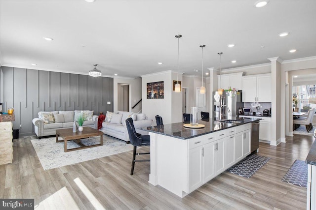 kitchen with crown molding, appliances with stainless steel finishes, a sink, and white cabinetry