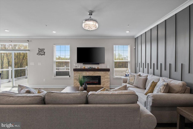 living room with plenty of natural light, a fireplace, baseboards, and ornamental molding