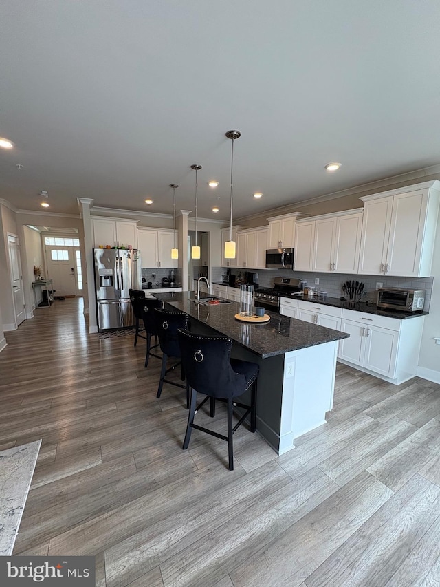 kitchen featuring a kitchen breakfast bar, a large island, light wood-style flooring, stainless steel appliances, and a sink