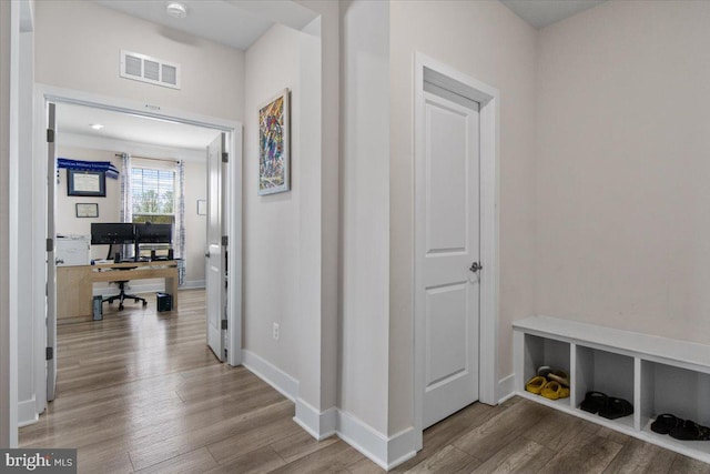 corridor featuring visible vents, baseboards, and wood finished floors