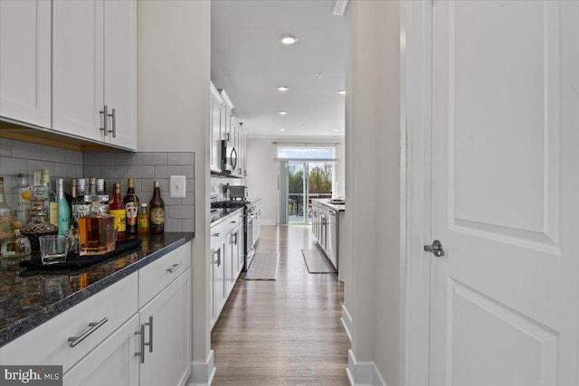 interior space featuring light wood-type flooring, recessed lighting, stainless steel appliances, baseboards, and backsplash