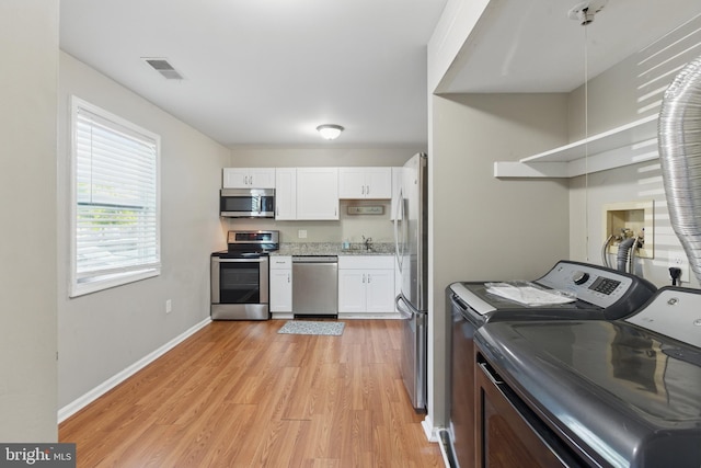 laundry area featuring washer and dryer, light wood-type flooring, and baseboards