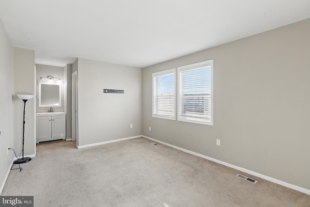 carpeted empty room with a sink and baseboards