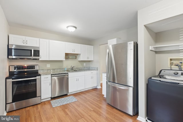 kitchen with stainless steel appliances, washer / dryer, a sink, and white cabinetry