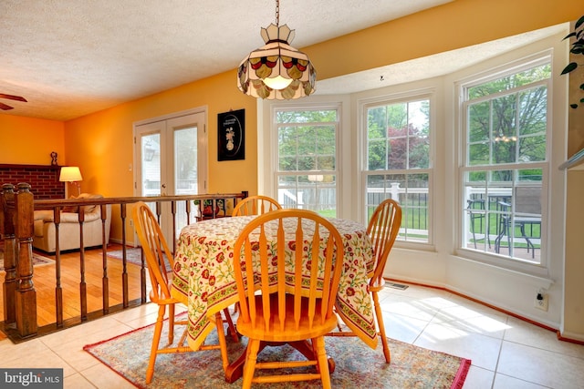 dining area with a textured ceiling, a healthy amount of sunlight, and light tile patterned floors