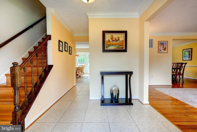 hallway with crown molding, baseboards, stairway, and light tile patterned flooring