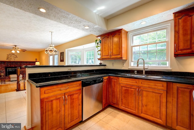 kitchen featuring a peninsula, stainless steel dishwasher, a sink, and a wealth of natural light