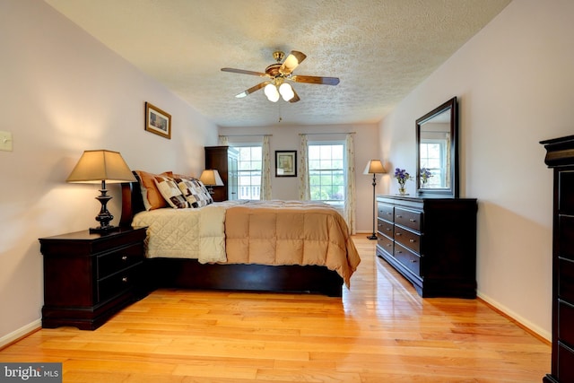 bedroom featuring baseboards, a ceiling fan, a textured ceiling, and light wood finished floors