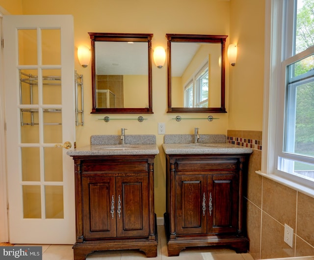 full bathroom featuring two vanities, a sink, and plenty of natural light