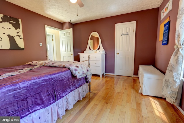 bedroom featuring light wood-style flooring, a textured ceiling, a ceiling fan, and baseboards
