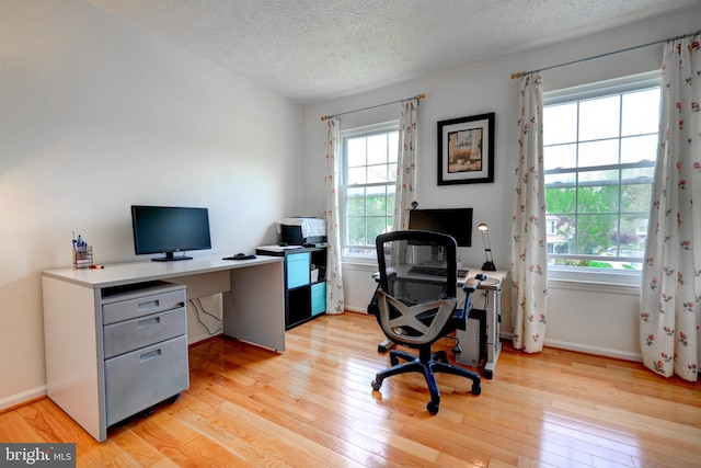home office with baseboards, light wood-style floors, and a textured ceiling