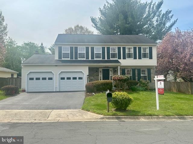 view of front of home featuring an attached garage, driveway, a front lawn, and fence