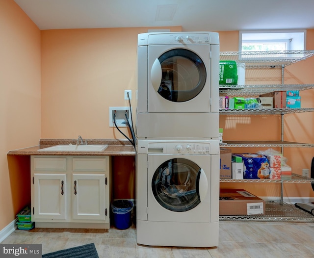 laundry area with stacked washer and clothes dryer, a sink, and cabinet space