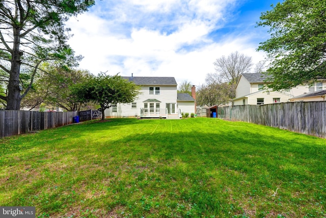 rear view of property featuring a fenced backyard, a deck, and a lawn
