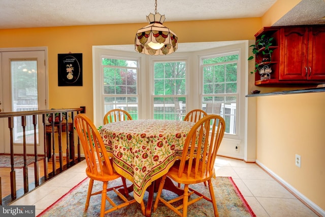dining room with a textured ceiling, light tile patterned floors, and a healthy amount of sunlight