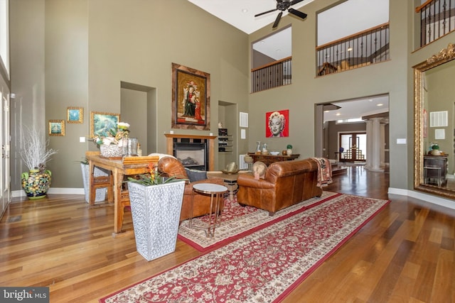 4083 Reels Mill Rd, Frederick, MD 21704 - living area featuring a glass covered fireplace, wood finished floors, decorative columns, a towering ceiling, and ceiling fan