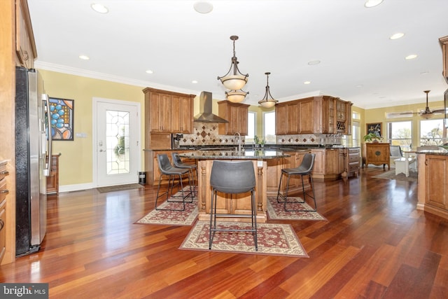 4083 Reels Mill Rd, Frederick, MD 21704 - kitchen with wall chimney range hood, brown cabinets, freestanding refrigerator, a kitchen island with sink, and a breakfast bar area