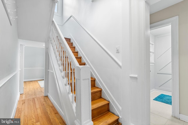 stairway with wood finished floors and baseboards