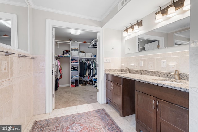 bathroom featuring tile patterned floors, a sink, visible vents, and tile walls