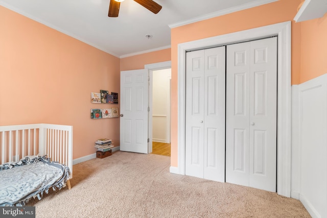 carpeted bedroom with baseboards, a closet, ornamental molding, and a ceiling fan