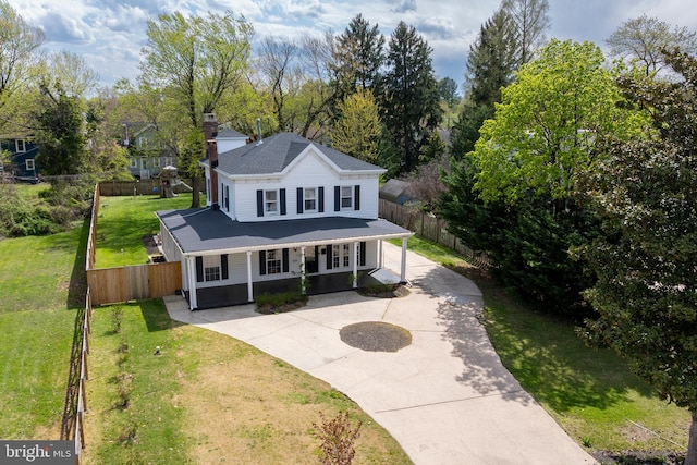 view of front facade with a front yard, a chimney, fence, and concrete driveway
